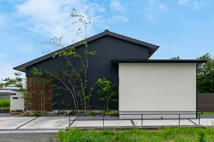 円窓から紅葉を眺めるシンプルな平屋の外観